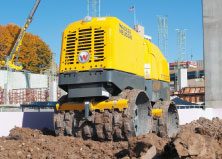 Wacker Neuson Remote-controlled trench roller on a mound of dirt in a construction site outside with a blue sky