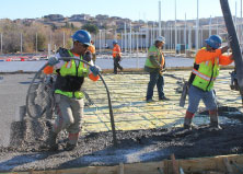 construction workers pouring concrete into wire form mesh