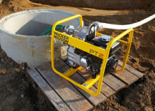 Wacker Nueson Centrifugal pumps on slats of wood on top of dirt pumping water out of a large concrete hole