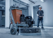 Husqvarna concrete surface floor grinder in a gray colored room with operator standing in the background
