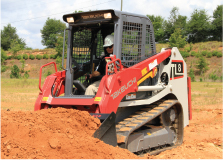 Takeuchi compact track loader shoveling red dirt into a pile in the middle of a field, available for rental and ideal for earth moving projects.