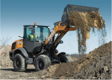 CASE rental wheel loader lifting a pile of dirt with its bucket to add to a mound, under a blue sky background, ideal for earth moving projects.