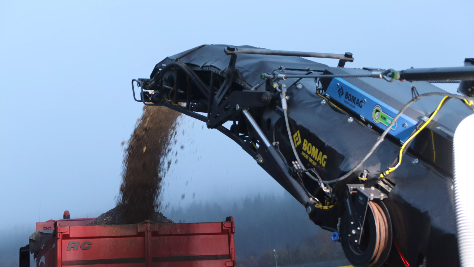 Bomag BM 2200 Milling Machine focus from the rear on the unloading of material onto a dump truck