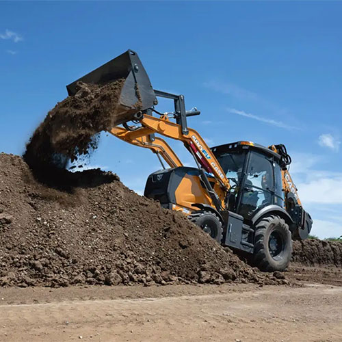 CASE 580EV Electric Backhoe Loader lifting dirt with bucket onto dirt pile under a blue sky