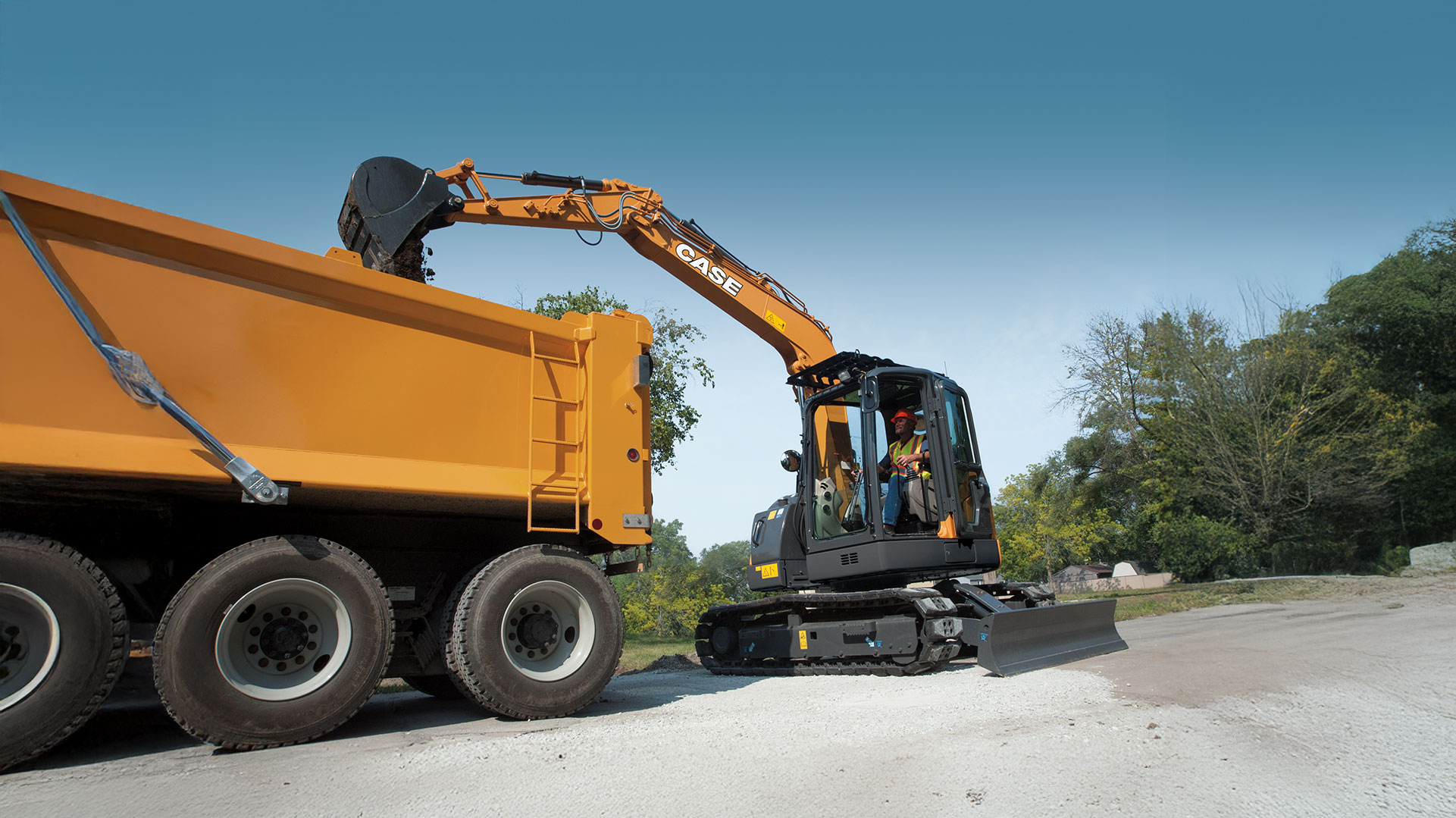 CASE CX75C SR dumping items into an orange dump truck on a street