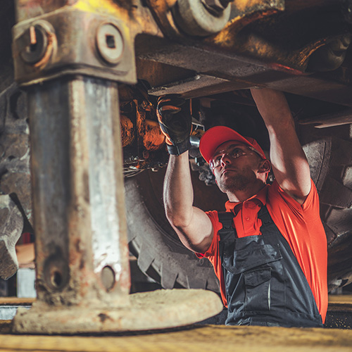 Small Excavator Repair and Maintenance. Caucasian Heavy Equipment Mechanic Trying to Find an Issue. Industrial Theme.