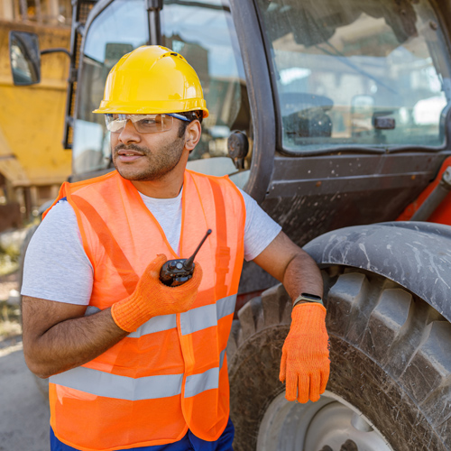 Construction Worker Leans on Vehicle Holding Walkie Talkie