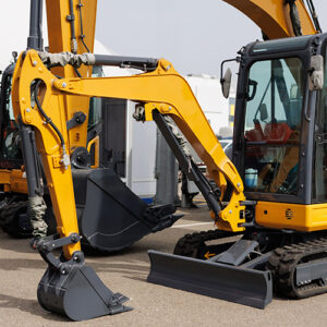 A series of bright yellow excavators stand on display at a construction equipment show.